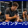 筋トレのセット間にベンチで休憩し、タイマーでインターバル時間を確認するトレーニー